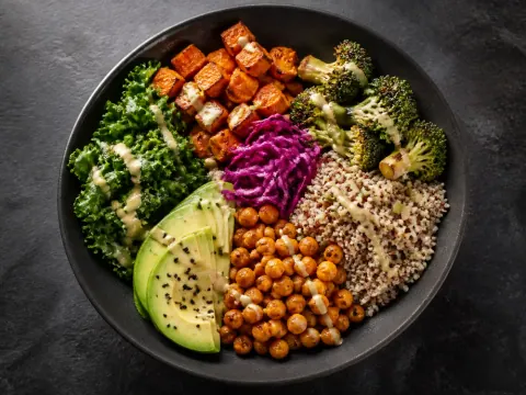 Representative a colorful vegan grain bowl with quinoa, roasted vegetables, chickpeas, avocado, greens, and tahini selected for GreenFare