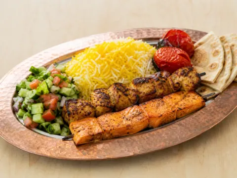 Representative a salmon kabob and chicken kabob combination with saffron rice, grilled tomato, salad, and pita selected for Moby Dick House of Kabob
