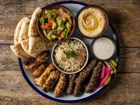 Representative a grilled chicken and kofta platter with hummus, rice, fattoush, pickles, tahini, and warm pita selected for Sakina Halal Grill