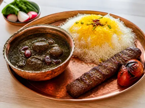 Representative Persian ghormeh sabzi stew with saffron rice beside a small koobideh skewer and grilled tomato selected for Shamshiry